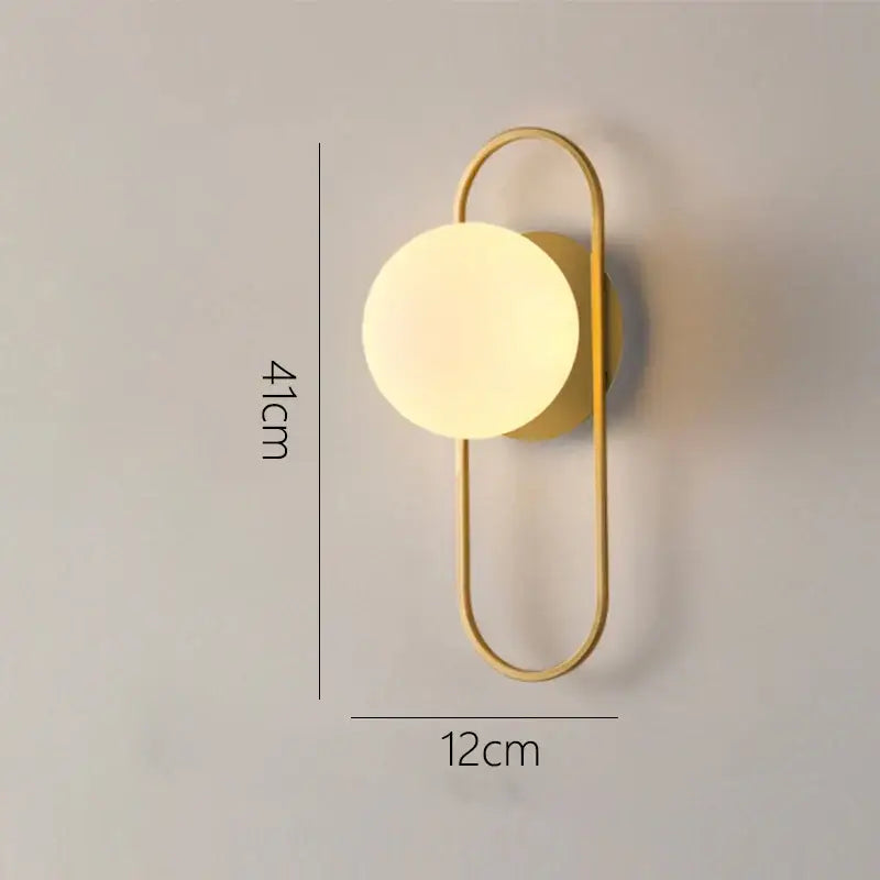 Modern minimalist gold wall lamp with glass gold led circular shade and elongated oval metal frame for bedroom decorbites glass gold