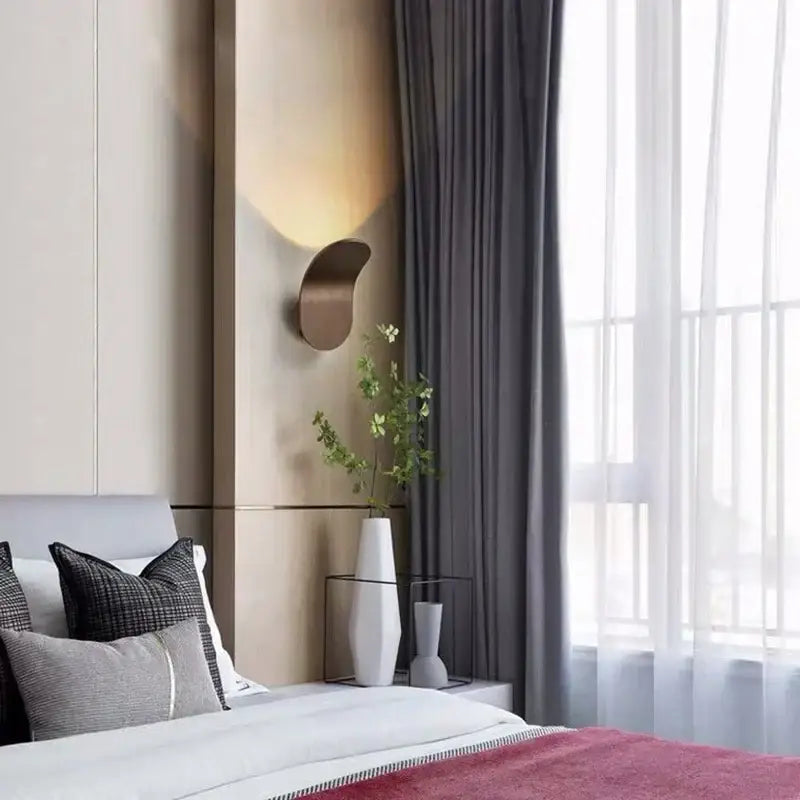 Modern minimalist gold and black led wall lamps featuring a bronze crescent-shaped wall sconce with warm ambient glow