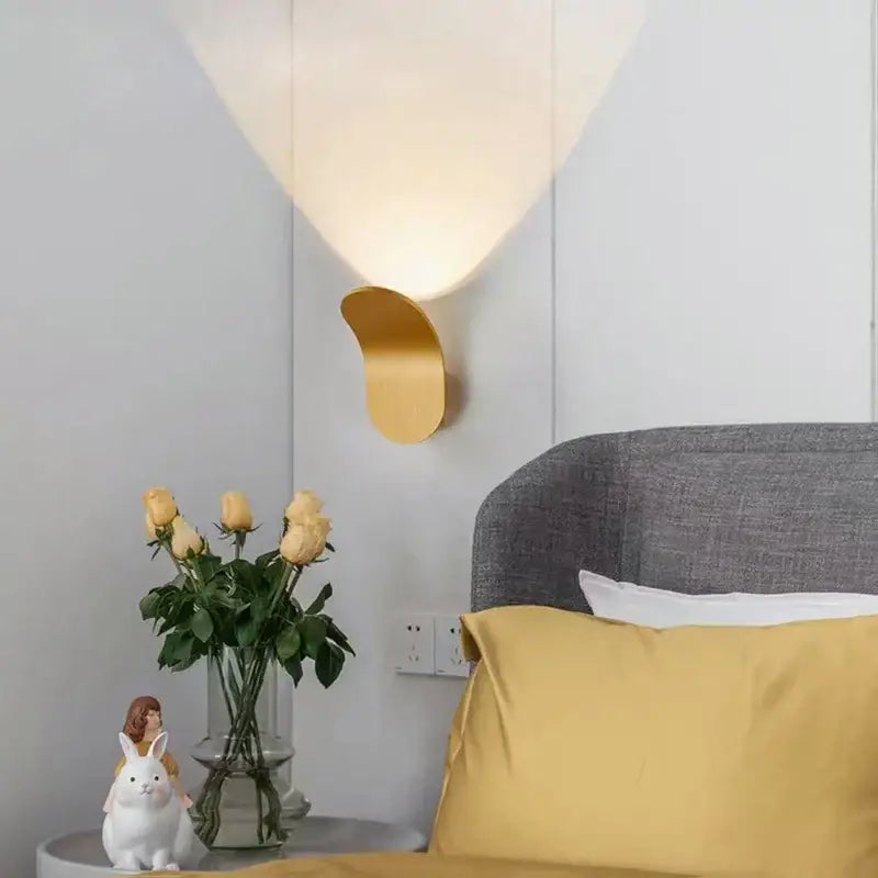 Modern minimalist gold and black led wall lamp with a sleek curved metallic base and soft diffused light for living room
