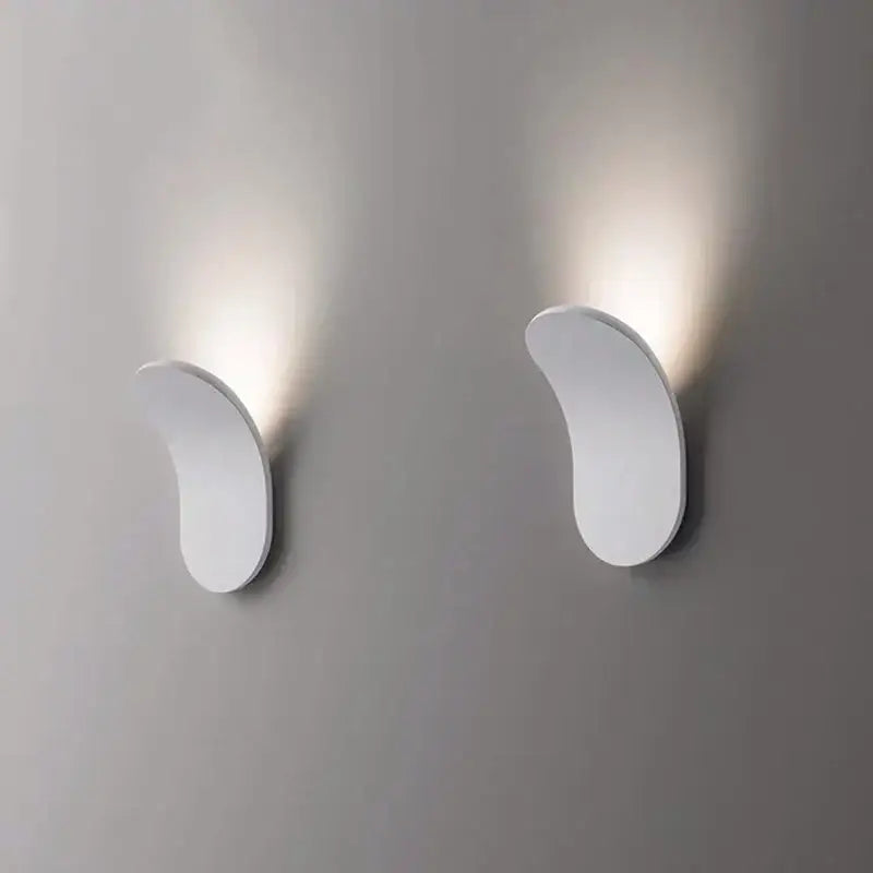 Modern minimalist gold and black led wall lamps with sleek curved white sconces emitting warm light for living room
