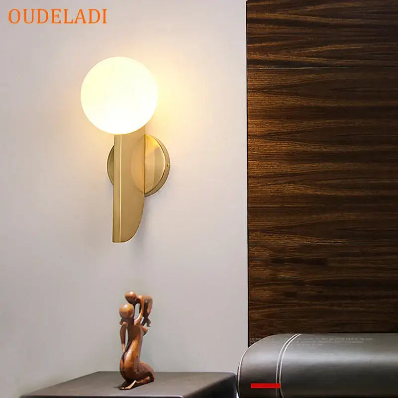 Gold-toned spherical wall lamp with minimalist modern design made of decorbites glass ball for bedroom lighting