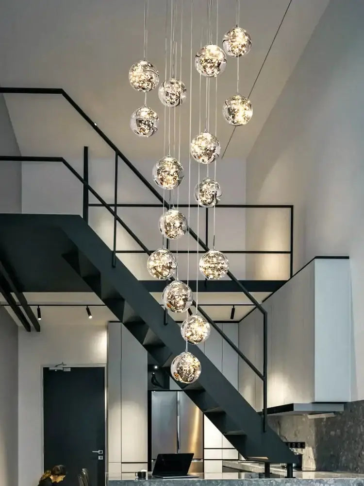 A modern minimalist decorbites glass chandelier with gold spherical orbs and metallic interiors for staircase lighting