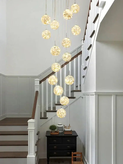 A modern minimalist gold decorbites glass chandelier with spherical globes emitting a warm golden glow for staircases