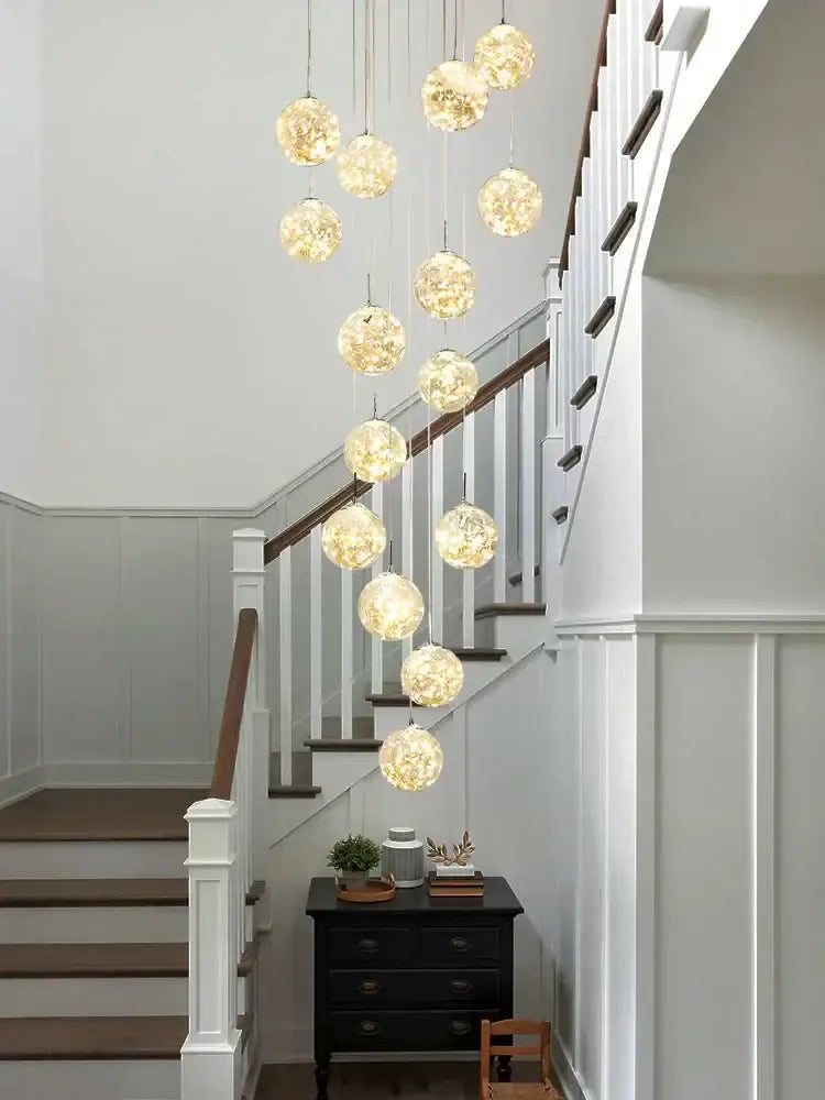 A modern minimalist gold decorbites glass chandelier with spherical globes emitting a warm golden glow for staircases