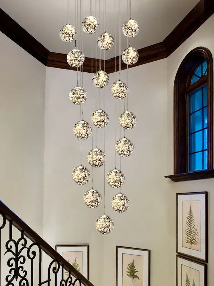 A modern minimalist gold decorbites glass chandelier with multiple faceted spherical glass orbs for staircase lighting