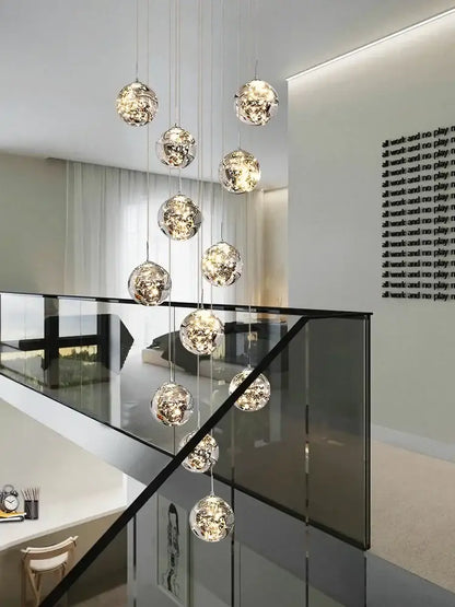 A modern minimalist gold decorbites glass chandelier with spherical orbs and intricate internal lighting for staircase lighting