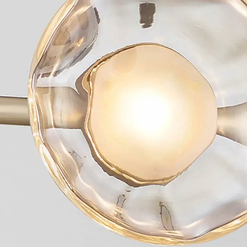 Modern minimalist gold glass led chandelier with a clear textured glass shade and metal accents for dining rooms