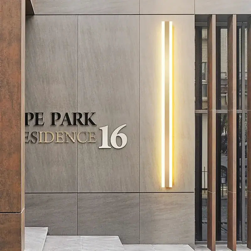 Modern minimalist gold led outdoor wall sconce illuminating metallic pe park residence 16 sign on textured gray wall decorbites gold led