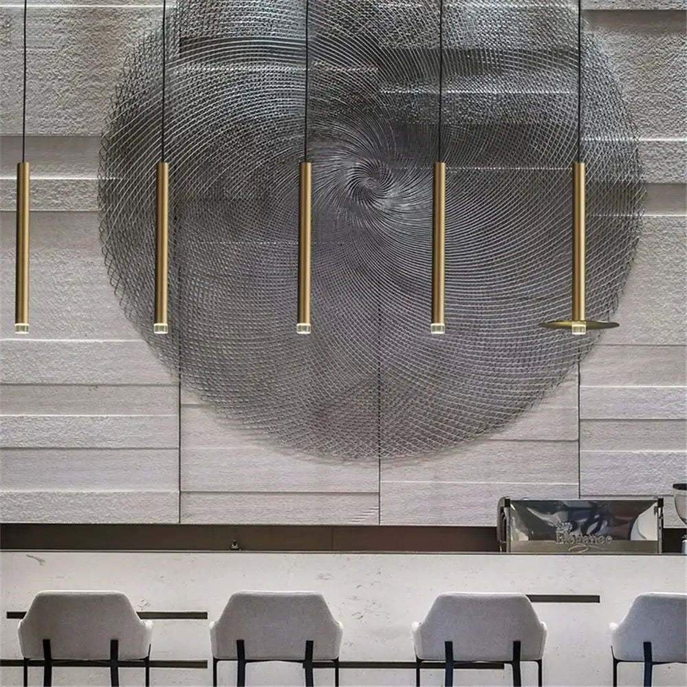 Five slender gold tube led pendant lights hanging in a row against a textured gray wall for kitchen dining decorbites