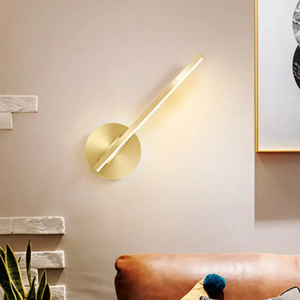 Modern minimalist gold tube stick wall sconce with a sleek angular design and circular base for bedroom lighting