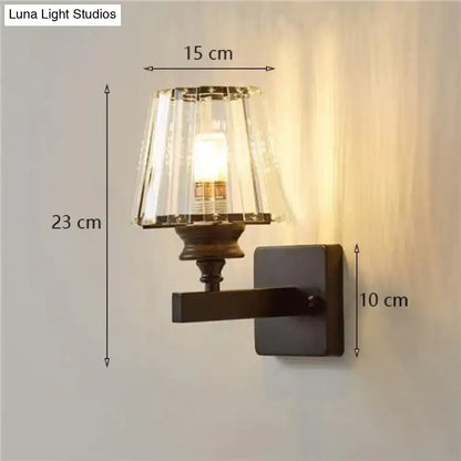 A modern minimalist wall lamp with dark bronze base and fluted crystal shade for elegant bedroom lighting