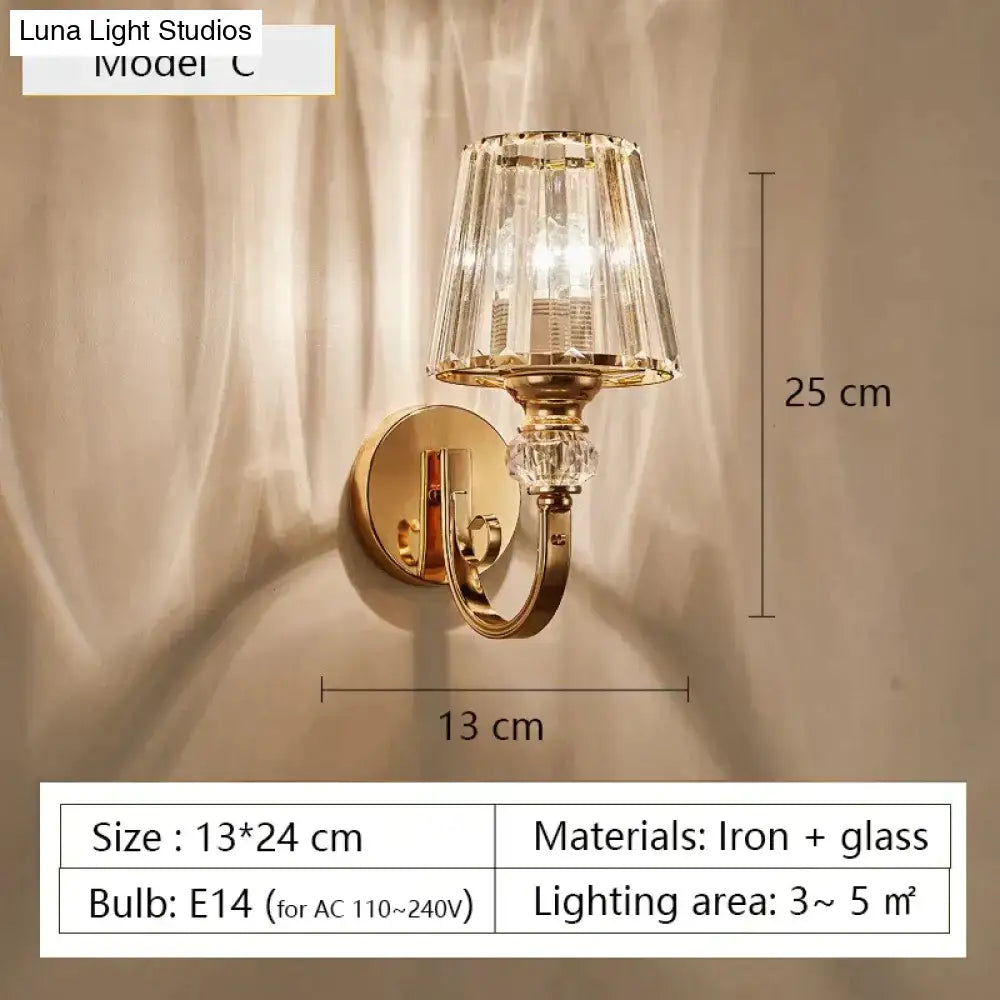 Modern minimalist gold wall lamp featuring a gold-toned sconce with faceted crystal glass shade and decorative accents