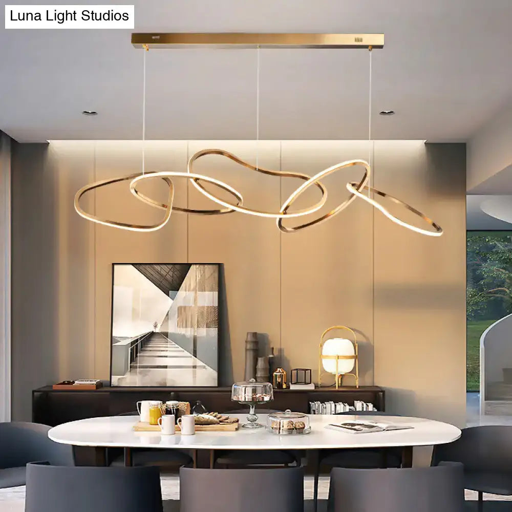 Modern minimalist golden led hanging light with interconnected circular rings suspended above a dining table