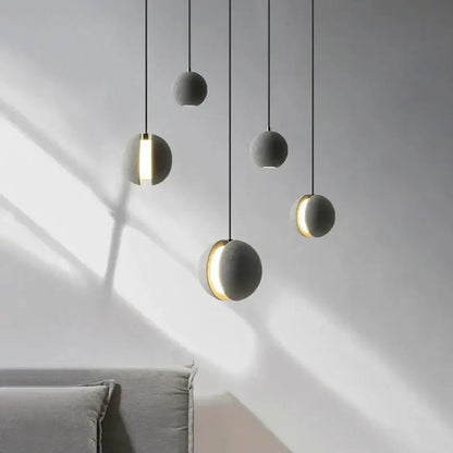 Modern minimalist gray and gold pendant light with matte spherical shades and warm gold rings for dining room decorbites cement planet chandelier
