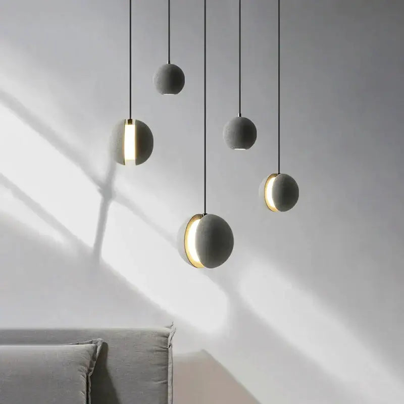 Modern minimalist gray and gold pendant light with matte spherical shades and warm gold rings for dining room decorbites cement planet chandelier