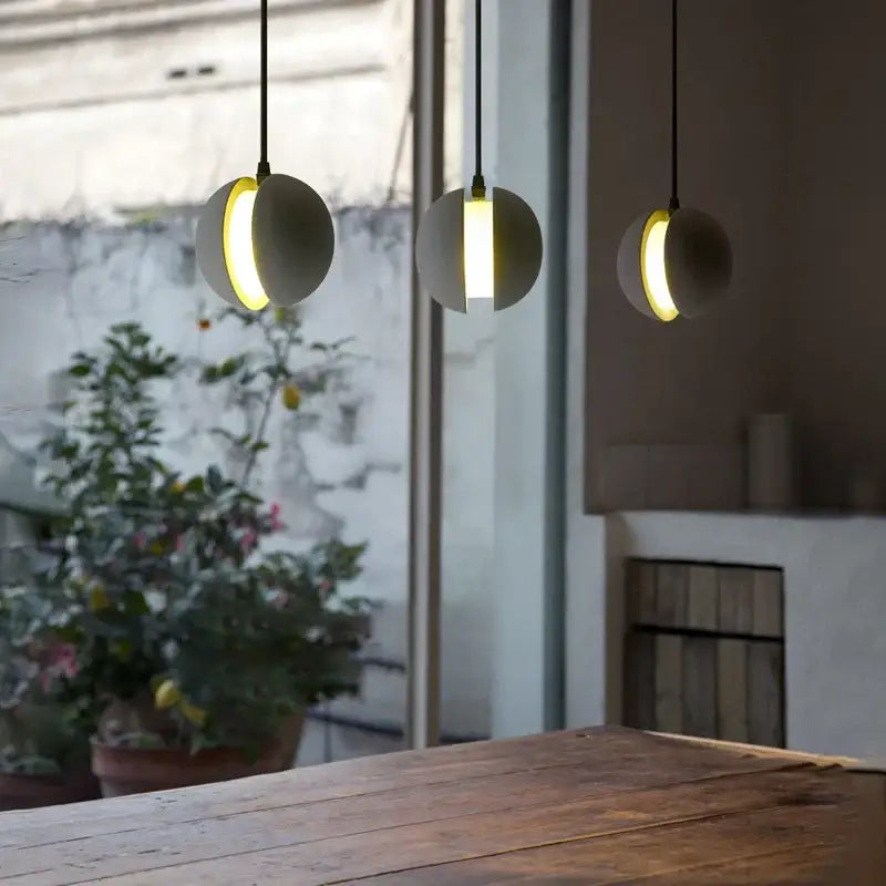 Modern minimalist gray and gold pendant light with matte gray cement planet chandelier and warm illumination for dining room decorbites