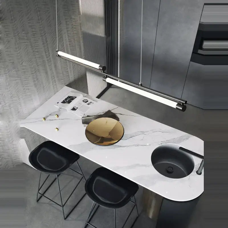 Modern minimalist led black gold designer chandelier above a bar counter with white marble top black sink and gold bowl centerpiece