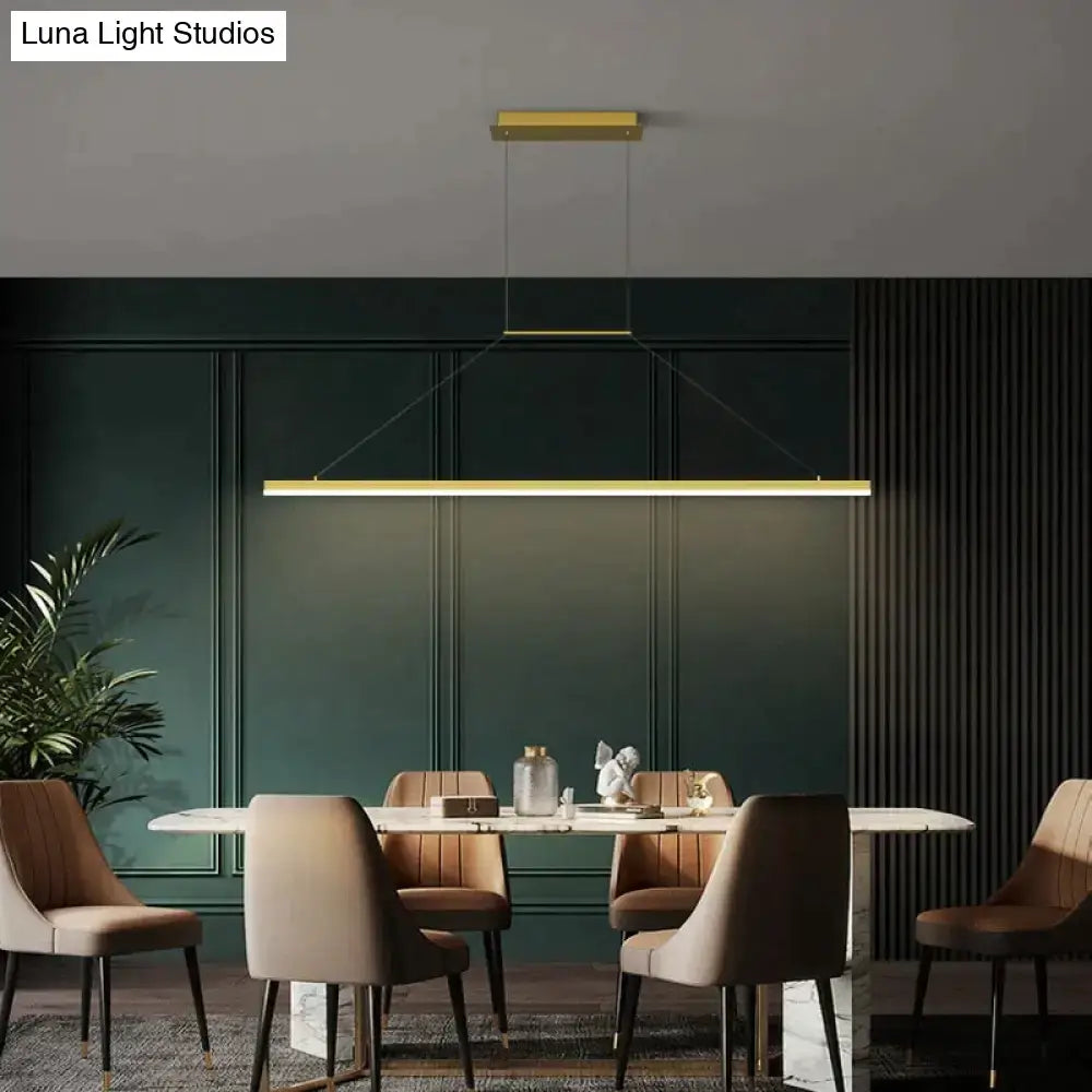 Gold-toned rectangular salix v pendant light with sleek modern minimalist led design hanging above dining table