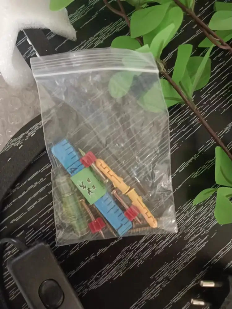 A clear plastic bag with colorful miniature carpenter’s tools next to a decorbites green plant mural wall lamp