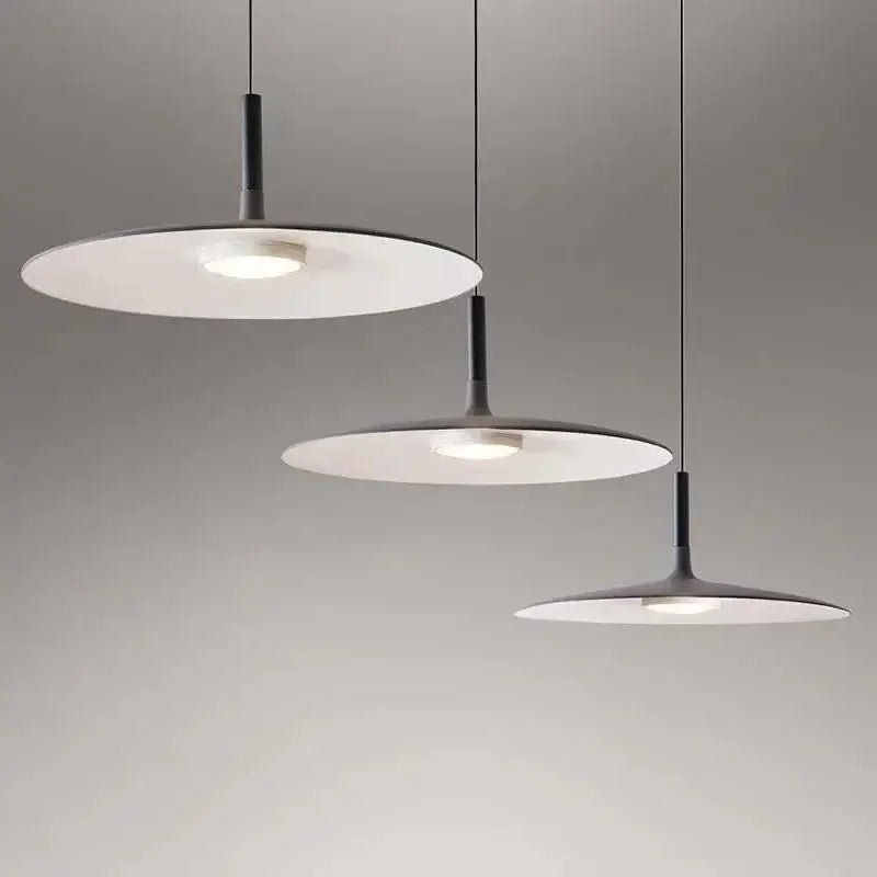 Three modern minimalist led ufo pendant lights with black stems and white shades emitting soft glow for dining room