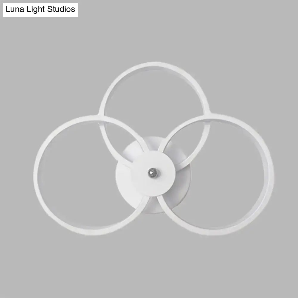 Modern minimalist white wall sconce light fixture with three interlocking rings for bedroom lighting