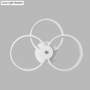 Modern minimalist white wall sconce light fixture with three interlocking rings for bedroom lighting