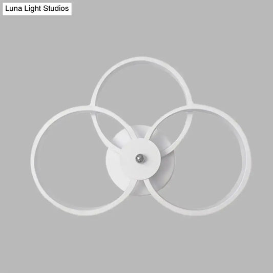 Modern minimalist white wall sconce light fixture with three interlocking rings for bedroom lighting