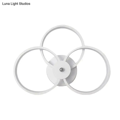 Modern minimalist white wall sconce light featuring three interlocking circular LED rings for bedroom illumination