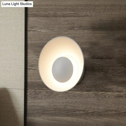 A sleek modern white wall lamp with circular design and soft ambient glow for minimalist living room décor