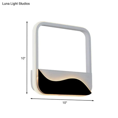 Modern minimalist white and black led wall mount sconce with sleek frame and wave-shaped panel emitting warm white light
