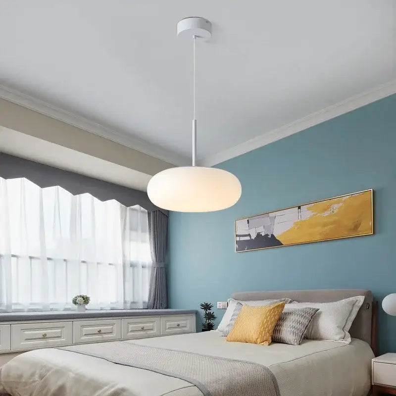 Modern minimalist white ceiling pendant lamp with sleek design hanging above the bed for kitchen or bedroom use