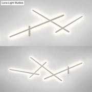 Modern minimalist white wall lamp with crossed linear arms and soft white LED glow for living room use