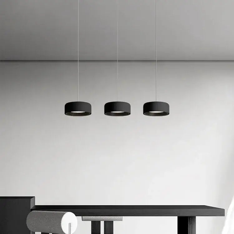 Three sleek black cylindrical pendant lights in a decorbites designer led chandelier for modern minimalist dining decor