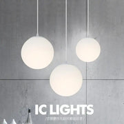 Three minimalist white frosted acrylic ball pendant lights hang against a concrete wall for dining room decorbites pendant light