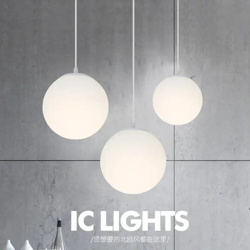 Three minimalist white frosted acrylic ball pendant lights hang against a concrete wall for dining room decorbites pendant light