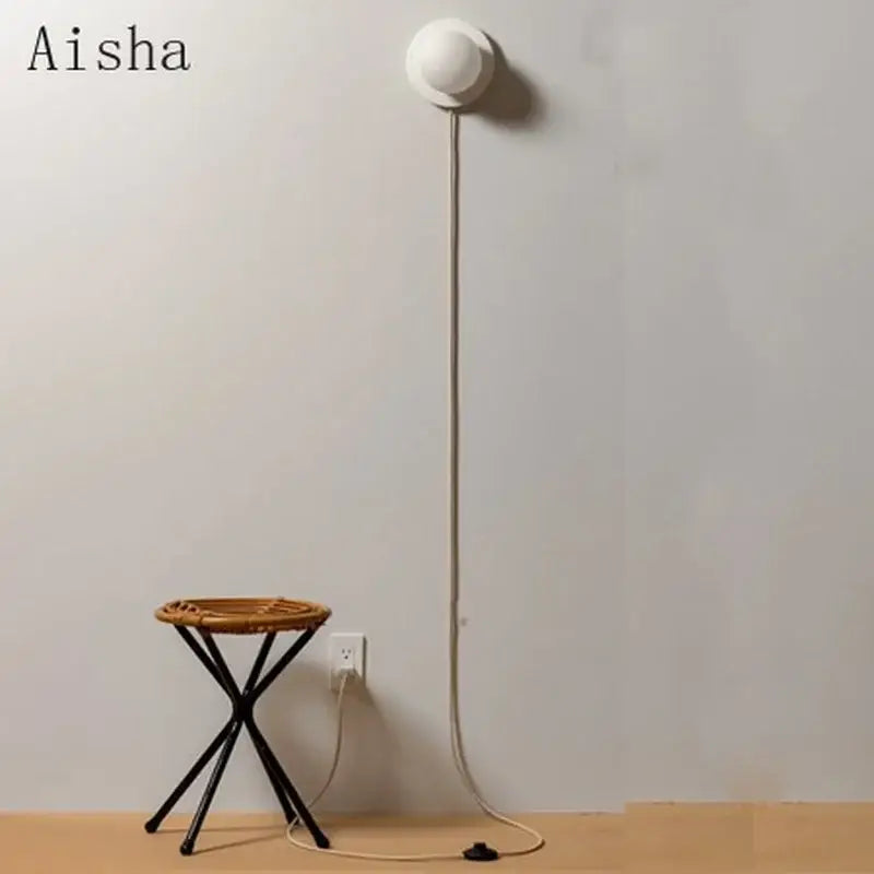 Modern minimalist white frosted glass ball wall light with slender cord and black plug for bedroom use