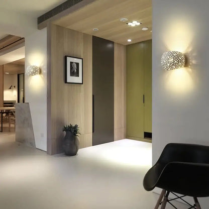 Modern minimalist white gypsum led wall lamp with spherical perforated matte surface and warm ambient lighting