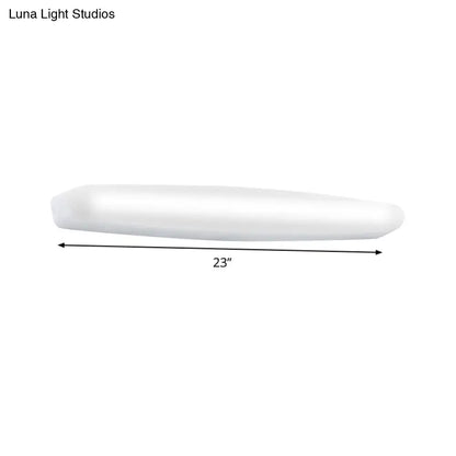 A sleek 23-inch white led wall light with modern elongated oval design emitting warm white light for bedroom use