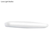 A sleek minimalist white led wall light with a rounded rectangular profile emitting warm white light for bedroom use