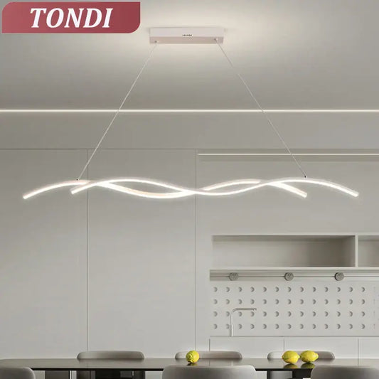A modern minimalist white led pendant light with a flowing wave design hanging in a dining room