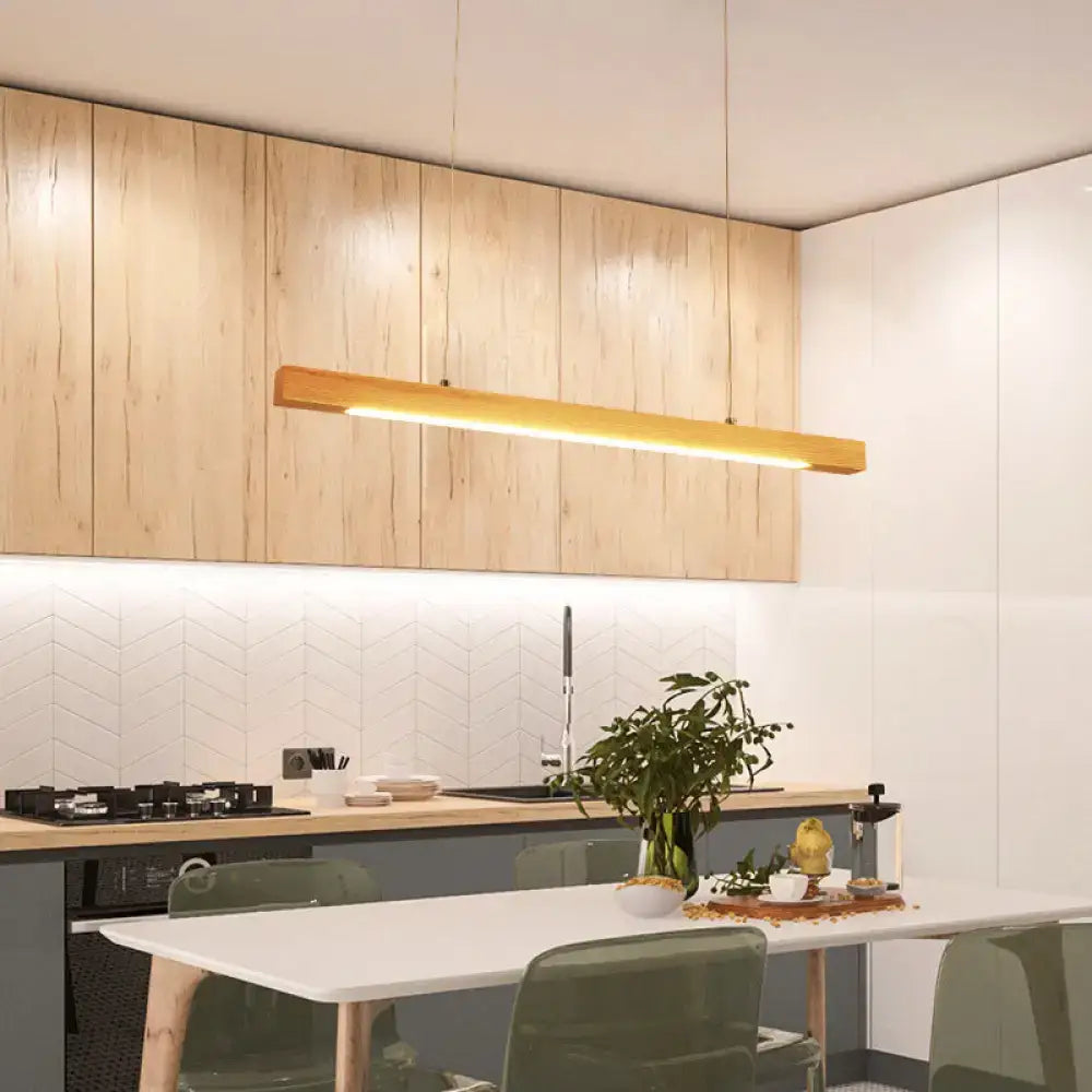 Modern minimalist wooden linear island pendant light with warm glowing illumination ideal for kitchen use