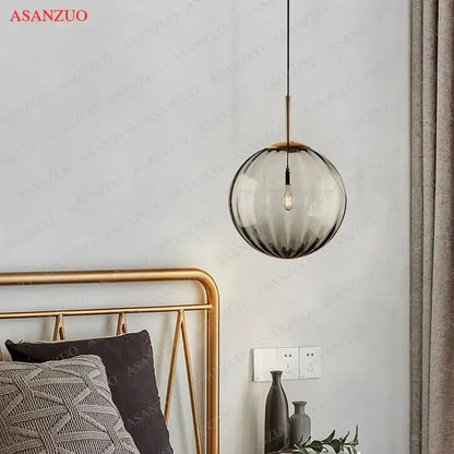 A modern multi color decorbites glass ball pendant lamp with gradient smoked glass and brass accents for dining room