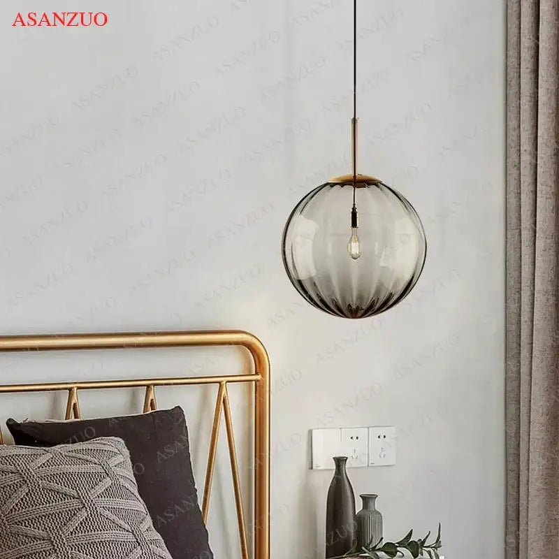 A modern multi color decorbites glass ball pendant lamp with gradient smoked glass and brass accents for dining room