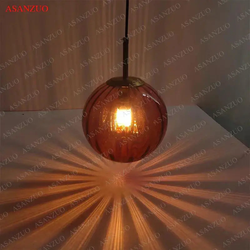 Modern multi color decorbites glass ball pendant lamp with warm amber glass globe, brass finish, and black cord for dining room decor