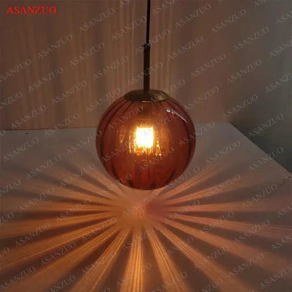 Modern multi color decorbites glass ball pendant lamp with warm amber glass globe, brass finish, and black cord for dining room decor