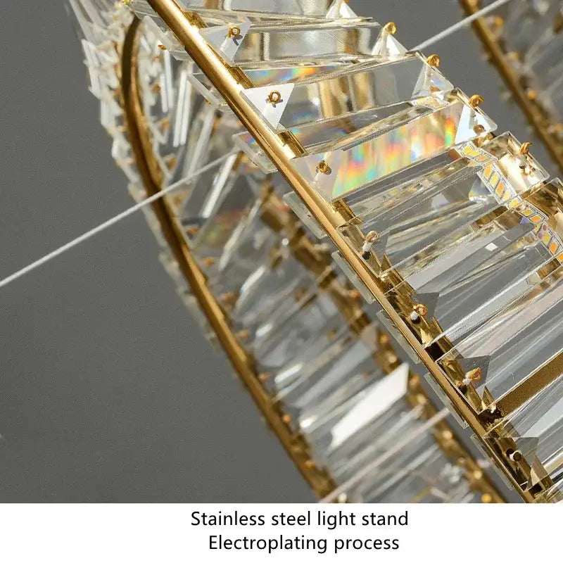 A modern multi tier gold decorbites crystal led chandelier with stainless steel frame and clear faceted crystal prisms
