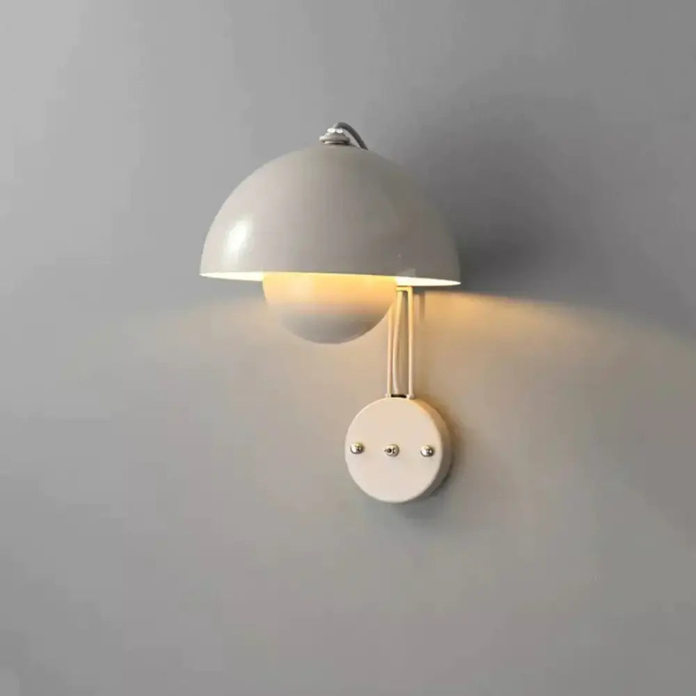 Cream-colored minimalist wall lamp with dome shade and brass base type finish for modern bedroom use
