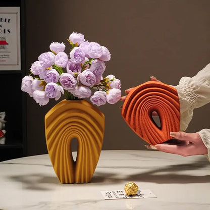A modern mustard yellow geometric folds ceramic vase with sculpted arch design holds light purple roses for decorbites decor