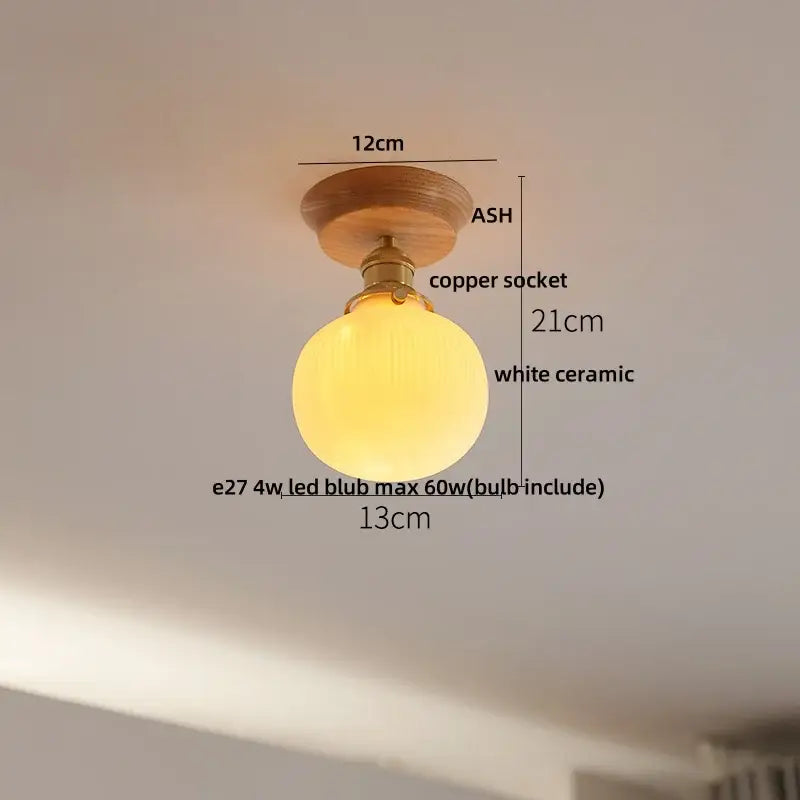 A warm glowing white ceramic globe ceiling lamp with brass copper socket and ash wood mount for modern nordic decorbites clear glass led