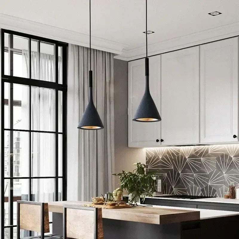 Two sleek black metal modern nordic pendant lights with conical shape and warm brass interior glow hang from ceiling